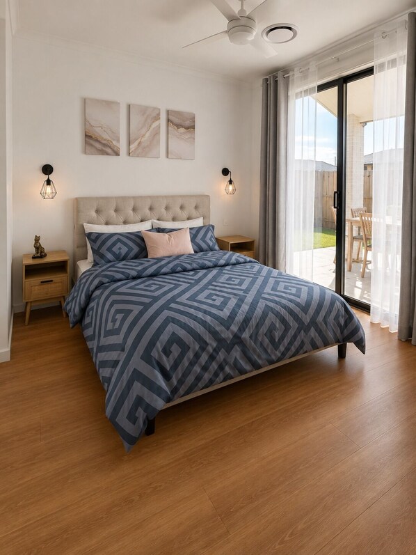 A bedroom with a large bed, two bedside tables, a ceiling fan, and a sliding glass door leading to an outdoor area. - Spacious 4 bed 2 bath family home - opposite park - 2 living areas (Greenbank)