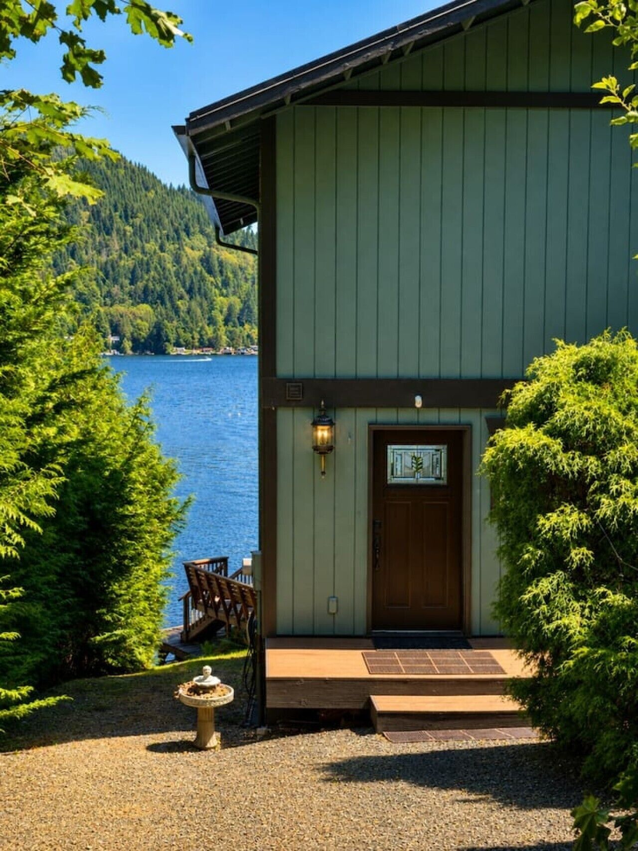 A building with a green exterior, a wooden door, and a small porch with a chair.