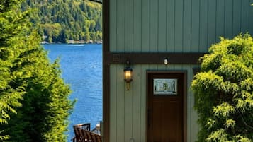 A building with a green exterior, a wooden door, and a small porch with a chair.