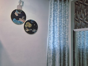 A wall with two circular wall art pieces and a patterned curtain.
