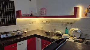 A kitchen with a stove, sink, and various kitchenware.