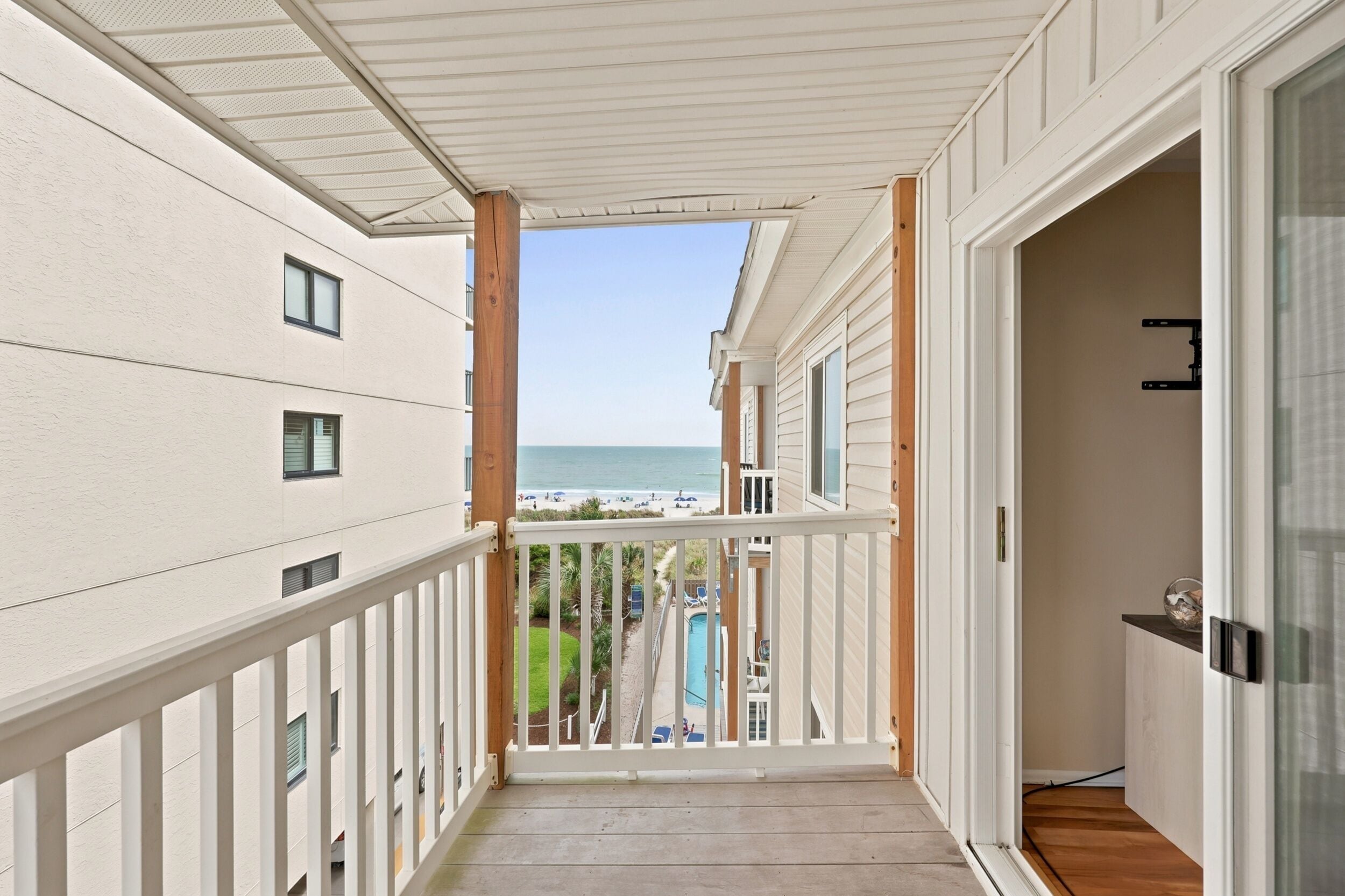 A corridor leading to a balcony with a view of the beach and ocean.