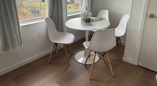 A room with a round table and four white chairs with wooden legs. - Cozy 2-bedroom house in soothing Taylor with cool AC (Taylor)