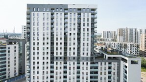 A high-rise residential building with multiple balconies, a flat facade, and a clear view of the surrounding urban area. - Starowiejska Baltic Comfort Apartment (Gdańsk)
