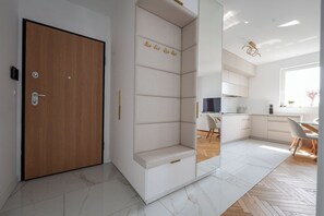 Un intérieur moderne avec une porte en bois, un banc intégré doté d’un espace de rangement, un coin cuisine et un espace repas.