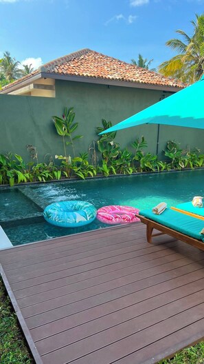 A swimming pool with two inflatable rings, a wooden deck, and a green wall with plants. - Eden Collection – 4 Bedroom Luxury Private Pool Villa in Thalpe (Talpe)