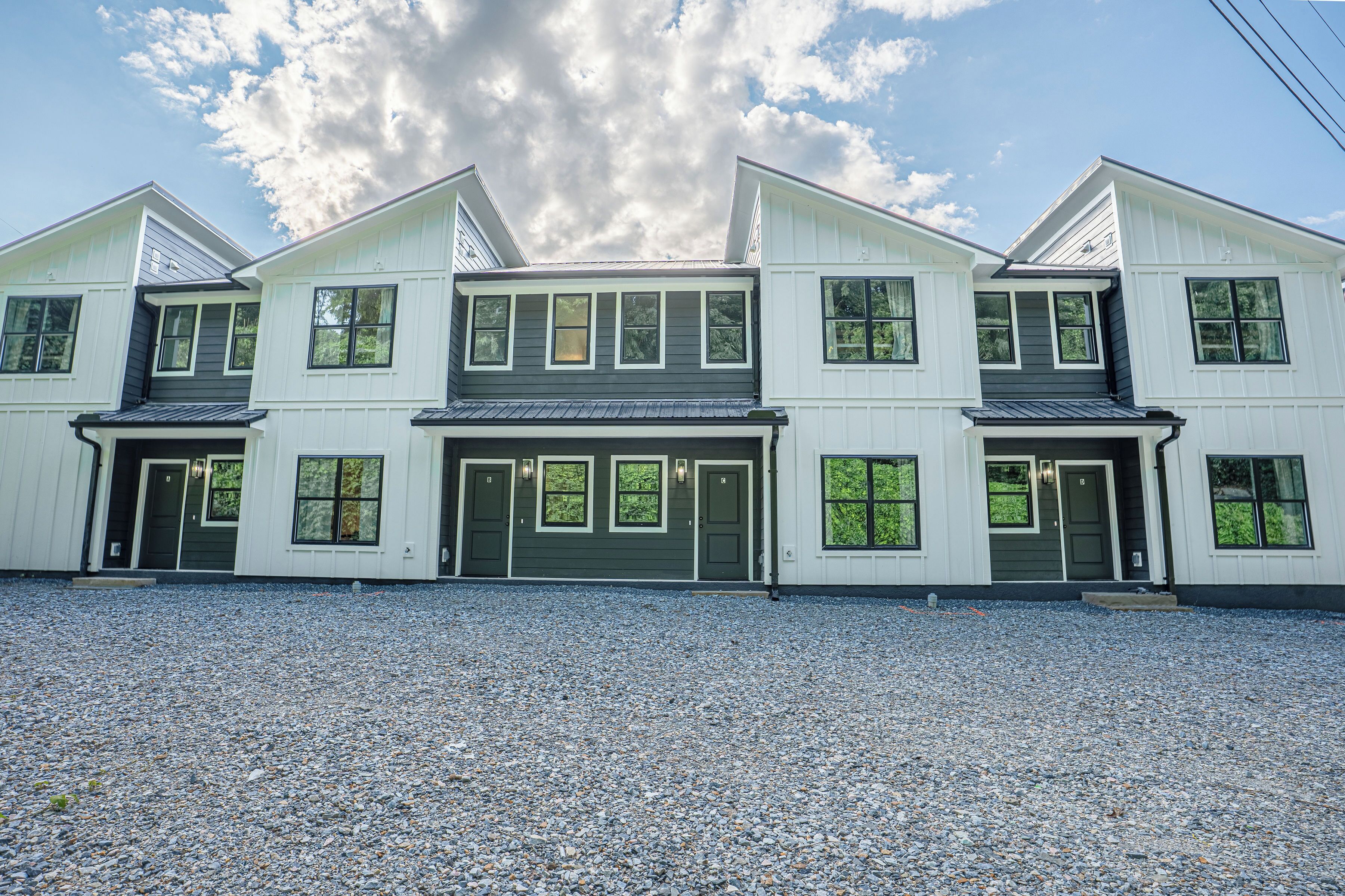 A two-story house with a gravel driveway and multiple windows.
