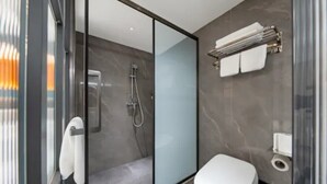 Uma casa de banho moderna com cabine de duche em vidro, sanita e porta-toalhas.