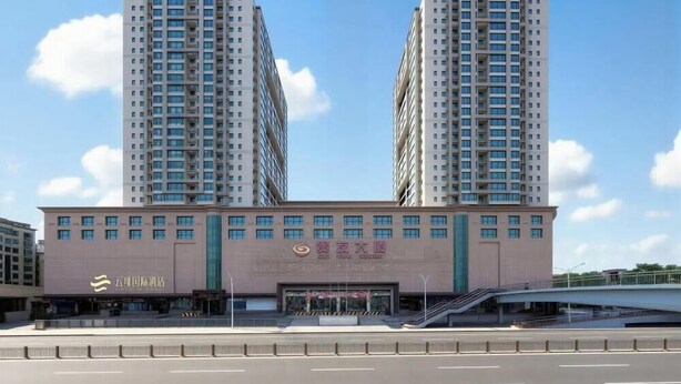 A multi-story hotel with a prominent entrance and a large parking area in front.