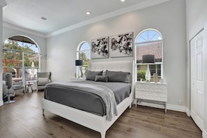 A bedroom with a bed, two wall-mounted lamps, a window with a view, and a ceiling fan. - Luxury Coral Springs Retreat (Coral Springs)