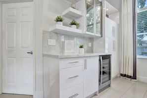 A modern kitchen with white cabinetry, marble countertops, and a built-in dishwasher. - Luxury Coral Springs Retreat (Coral Springs)