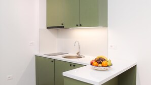 Uma cozinha com bancada branca, pia e uma tigela de frutas.