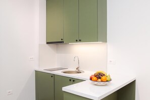 Eine Küche mit weißer Arbeitsplatte, einem Spülbecken und einer Obstschale.