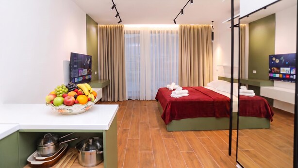 Quarto de hotel com cama, secretária com uma cesta de frutas, televisão e espelho.