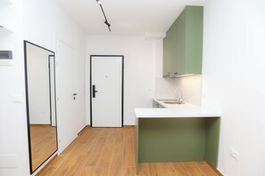 A compact kitchen with a white countertop, a green cabinet above the sink, and a door leading to another room. - Palm Olive Studio, Vlore, Albania (Vlore)