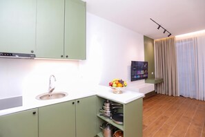 Eine moderne Küche mit grünen Schränken, einem Edelstahlspülbecken und einer Obstschale auf der Arbeitsplatte.