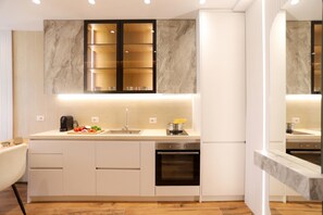 A modern kitchen with a marble backsplash, built-in cabinets, and a stainless steel range hood.