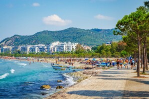 Une plage avec des gens, des bateaux et des bâtiments en arrière-plan.
