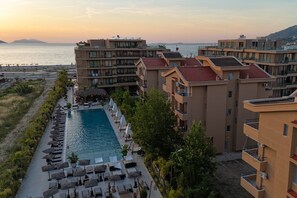 Ein Resort mit Schwimmbad, Liegestühlen und Meerblick.
