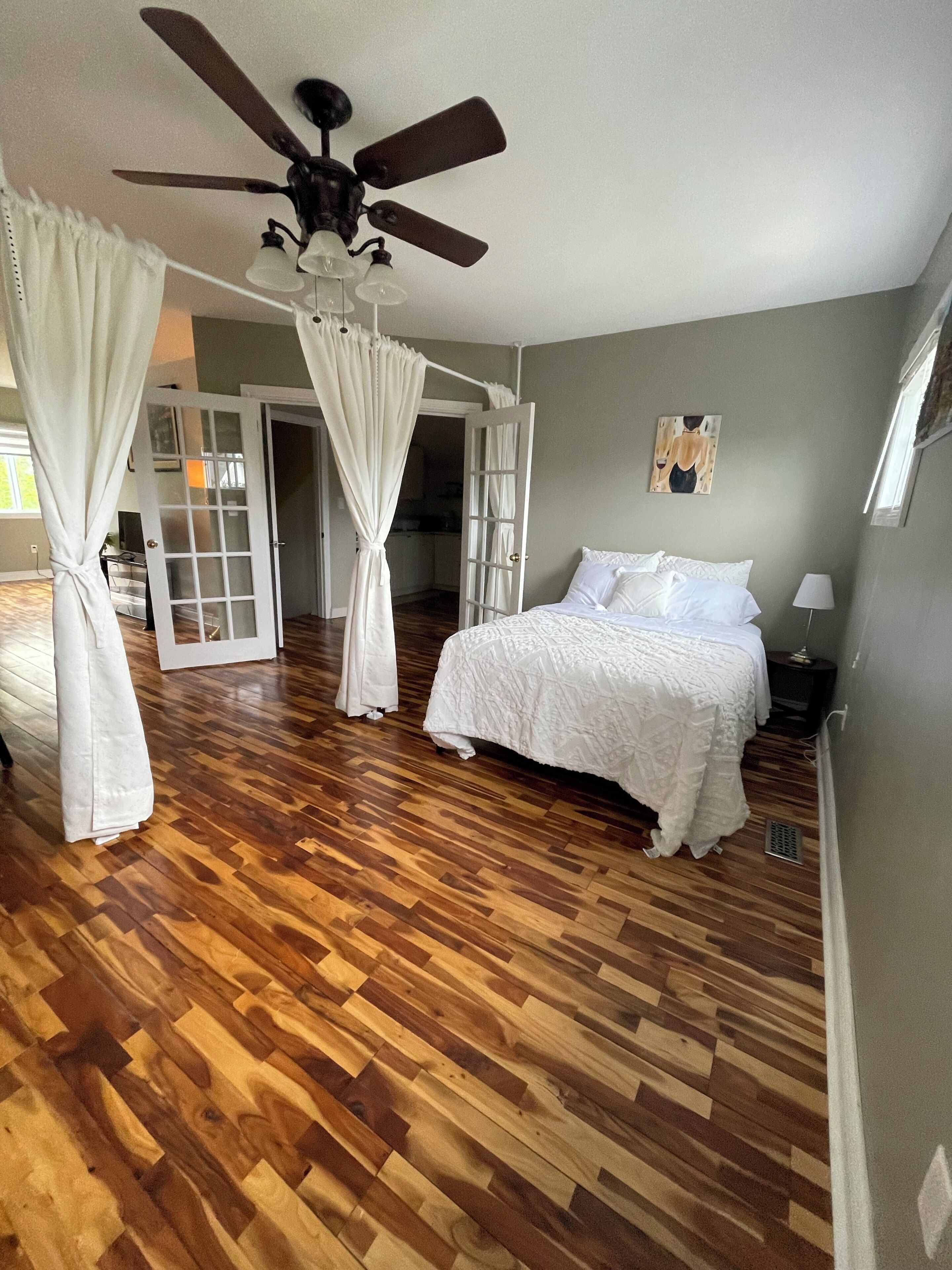 A bedroom with a bed, a ceiling fan, and a window.