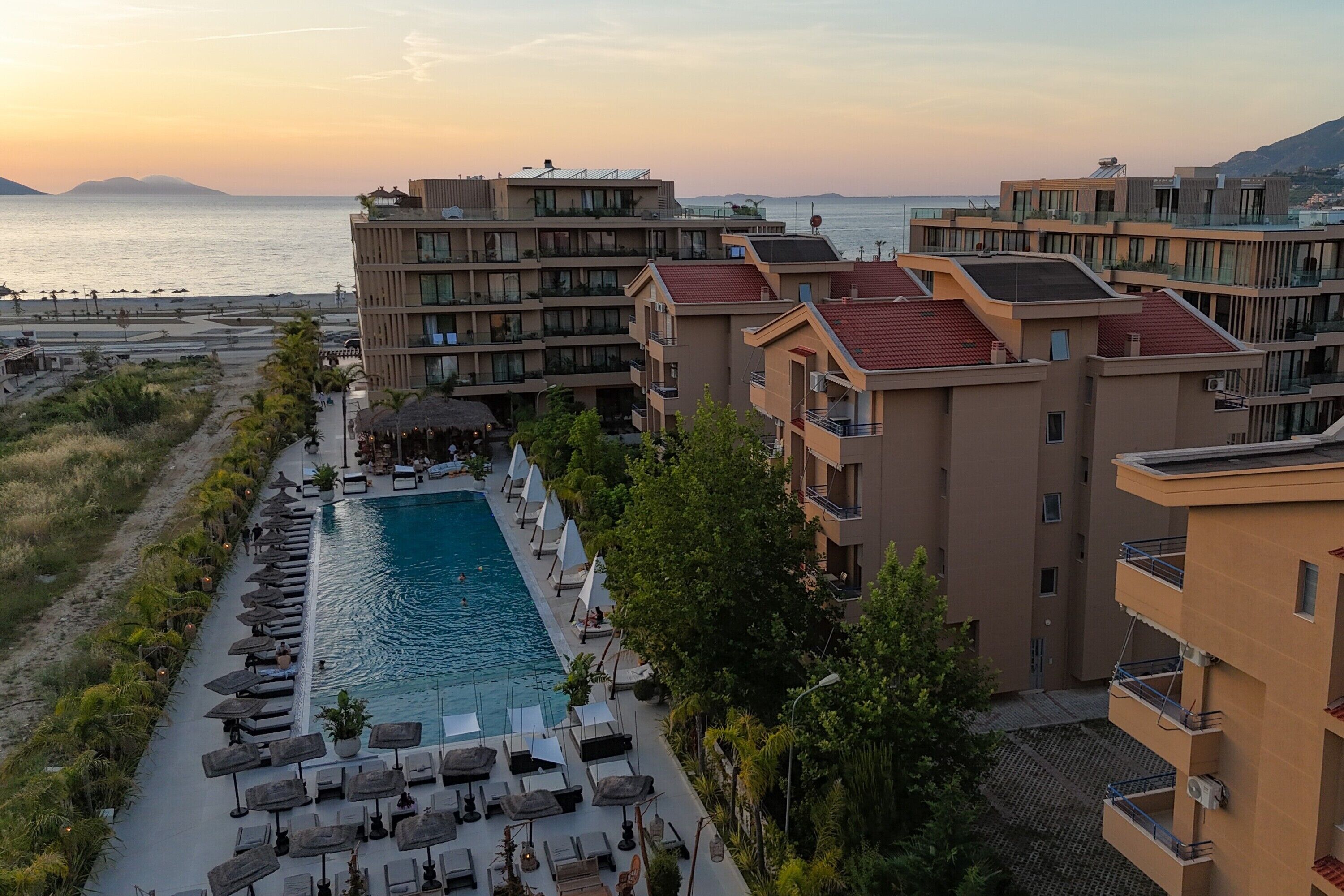 A hotel with a swimming pool, lounge chairs, and a view of the sea.