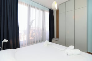 Ein Hotelzimmer mit Bett, Nachttisch, Kleiderschrank und einem Fenster mit Vorhängen.