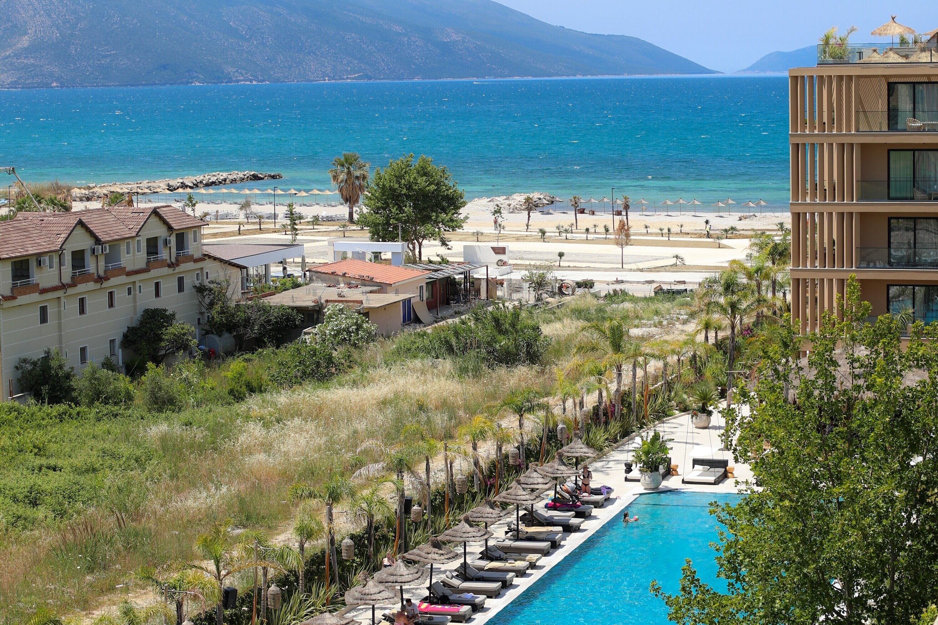 A resort with a pool, beach, and mountain views.