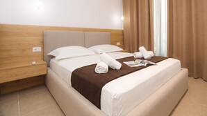 Une chambre d’hôtel avec un lit, une table de chevet, une lampe et une fenêtre avec des rideaux.