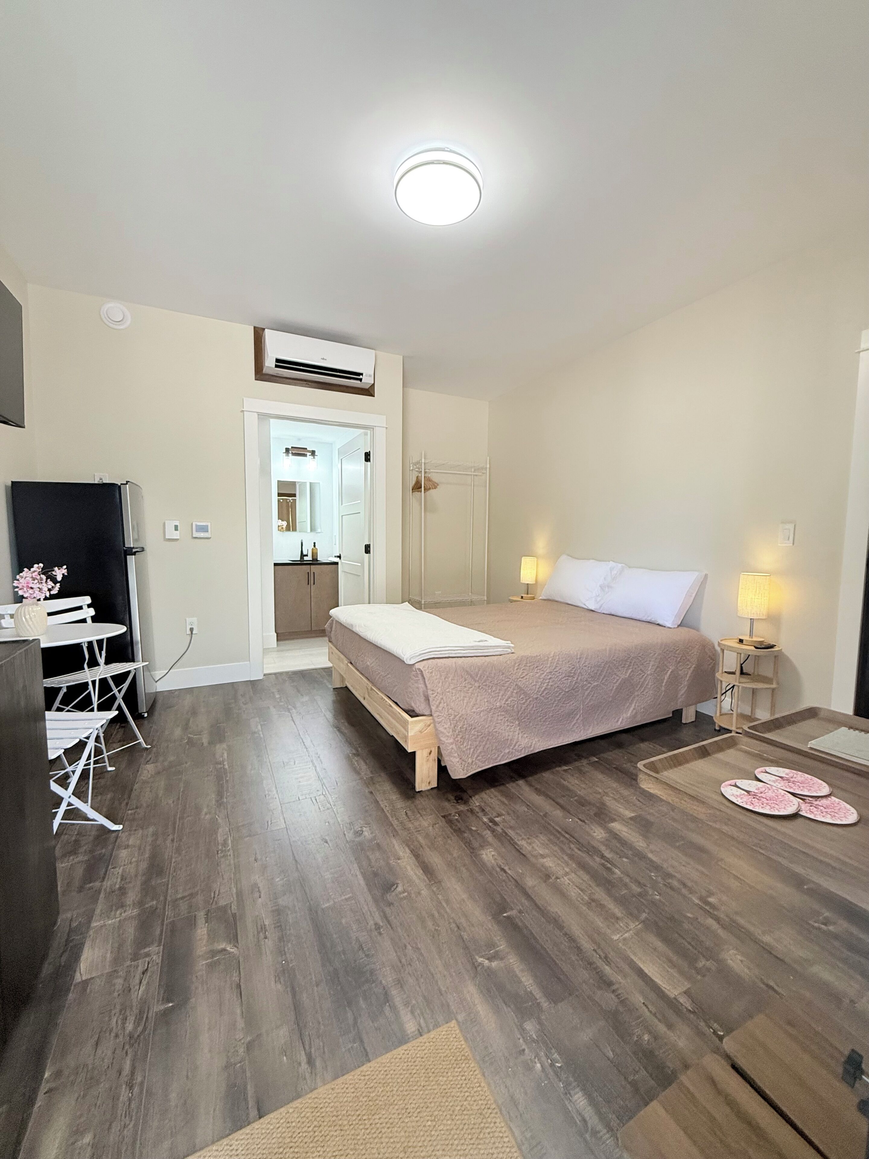 A bedroom with a bed, bedside tables, a desk, and a chair.