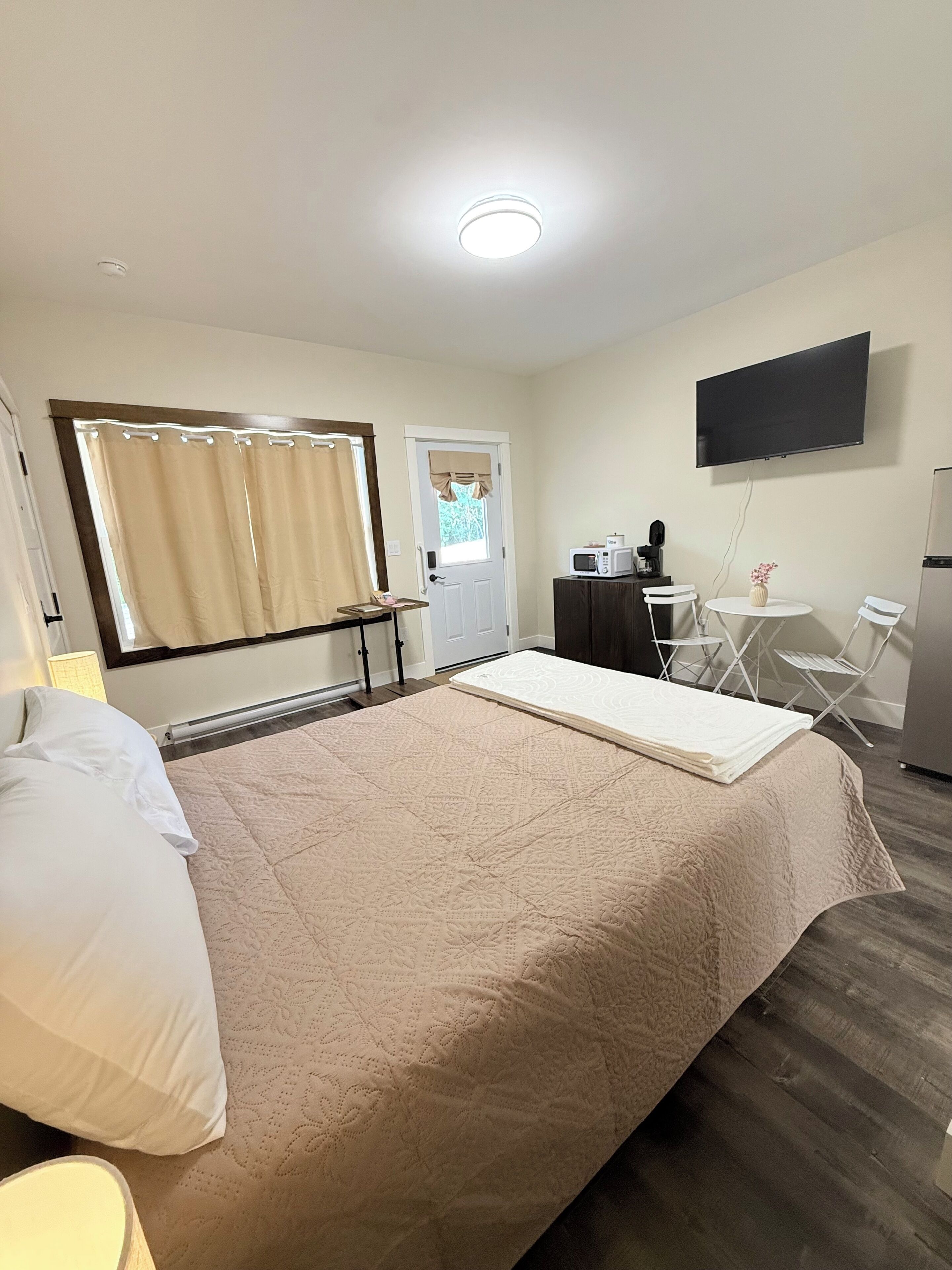 Ett hotellrum med en säng, ett skrivbord med en dator, en tv och en mikrovågsugn.