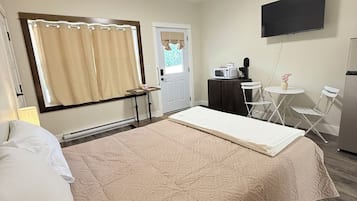 Ett hotellrum med en säng, ett skrivbord med en dator, en tv och en mikrovågsugn.