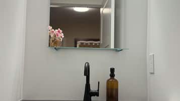A bathroom with a black sink, a mirror, a bottle of soap, and a towel.