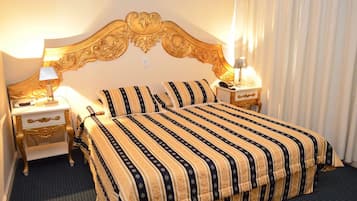 Een hotelkamer met een groot bed, twee nachtkastjes en een decoratief hoofdeinde.