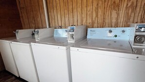 A row of white Whirlpool washing machines in a wooden room with a sloped ceiling. - May's Corner Cabin (Sturgis)