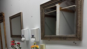 A bathroom with three sinks, each with a mirror above. There are potted plants with flowers on the counter. - May's Corner Cabin (Sturgis)