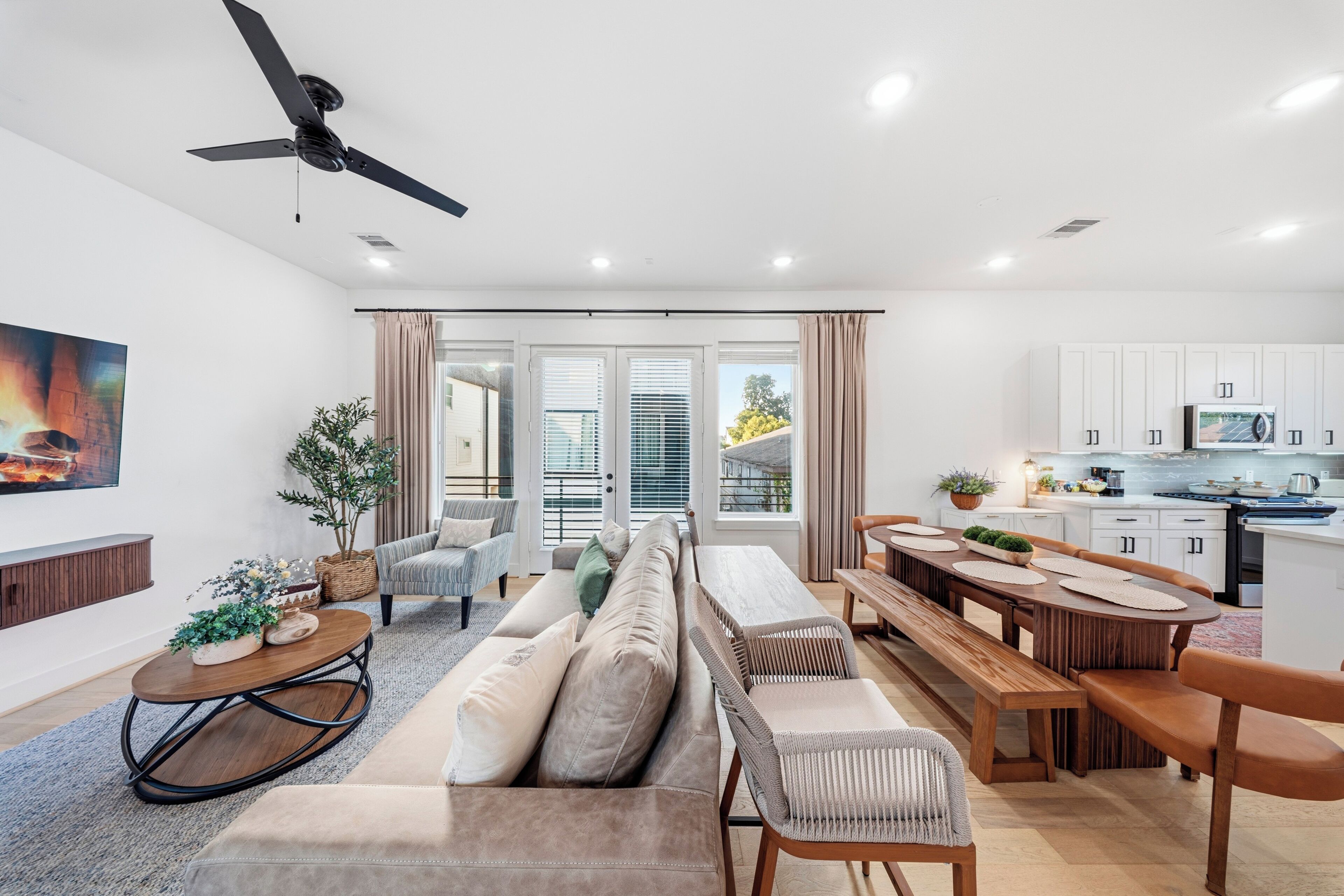 A modern living room with a sofa, a dining table, and a kitchen area with cabinets and appliances.