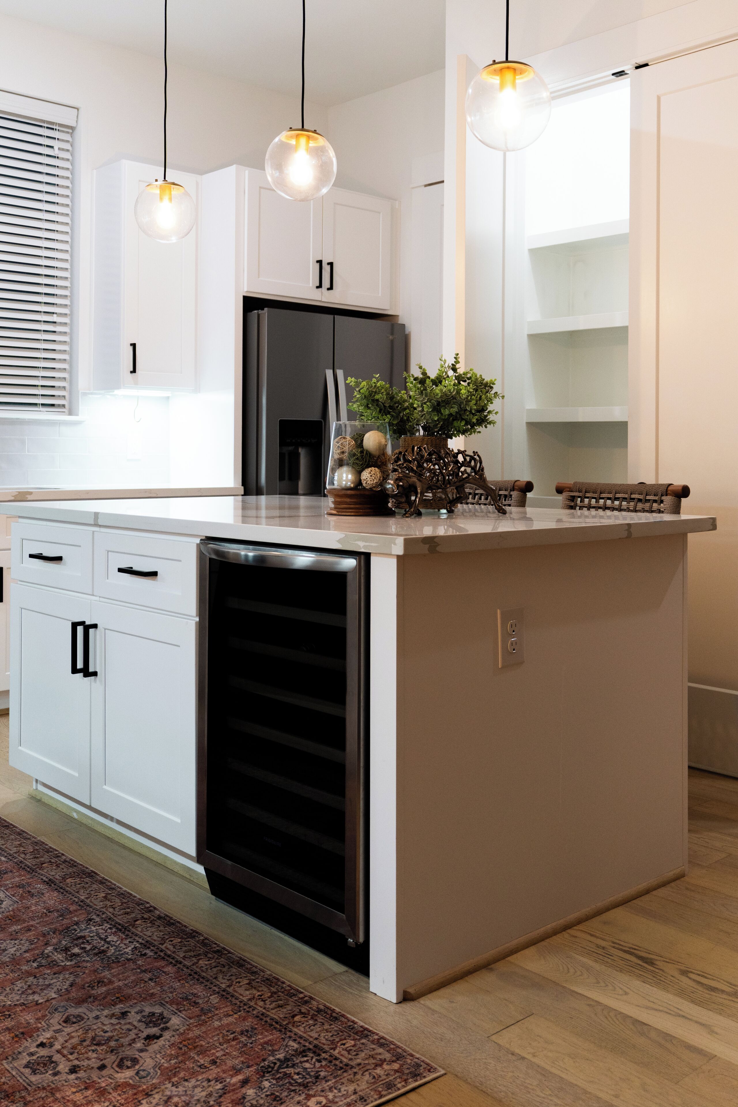 A modern kitchen with white cabinetry, a built-in dishwasher, and a central island with a sink.