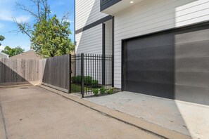 Eine moderne Doppelgarage mit schwarzem Tor, einem Holzzaun und einem kleinen Gartenbereich mit Pflanzen.