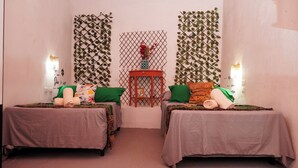 A room with two beds, each with a green pillow and a rolled towel. There is a small red table between the beds with a picture frame on it. - Hotel El Salvador Santa Ana (Santa Ana)