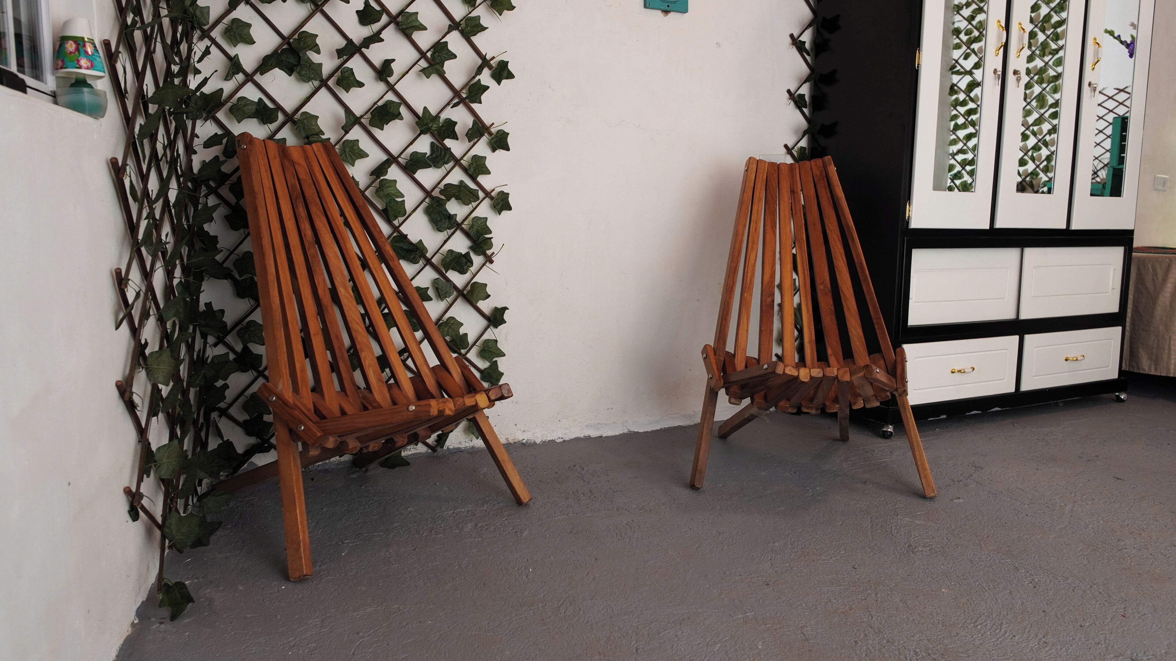 Two wooden chairs against a wall with a lattice design.