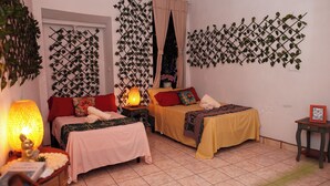 A hotel room with two beds, a nightstand with a lamp, a small table with a picture frame, and decorative vines on the walls. - Hotel El Salvador Santa Ana (Santa Ana)