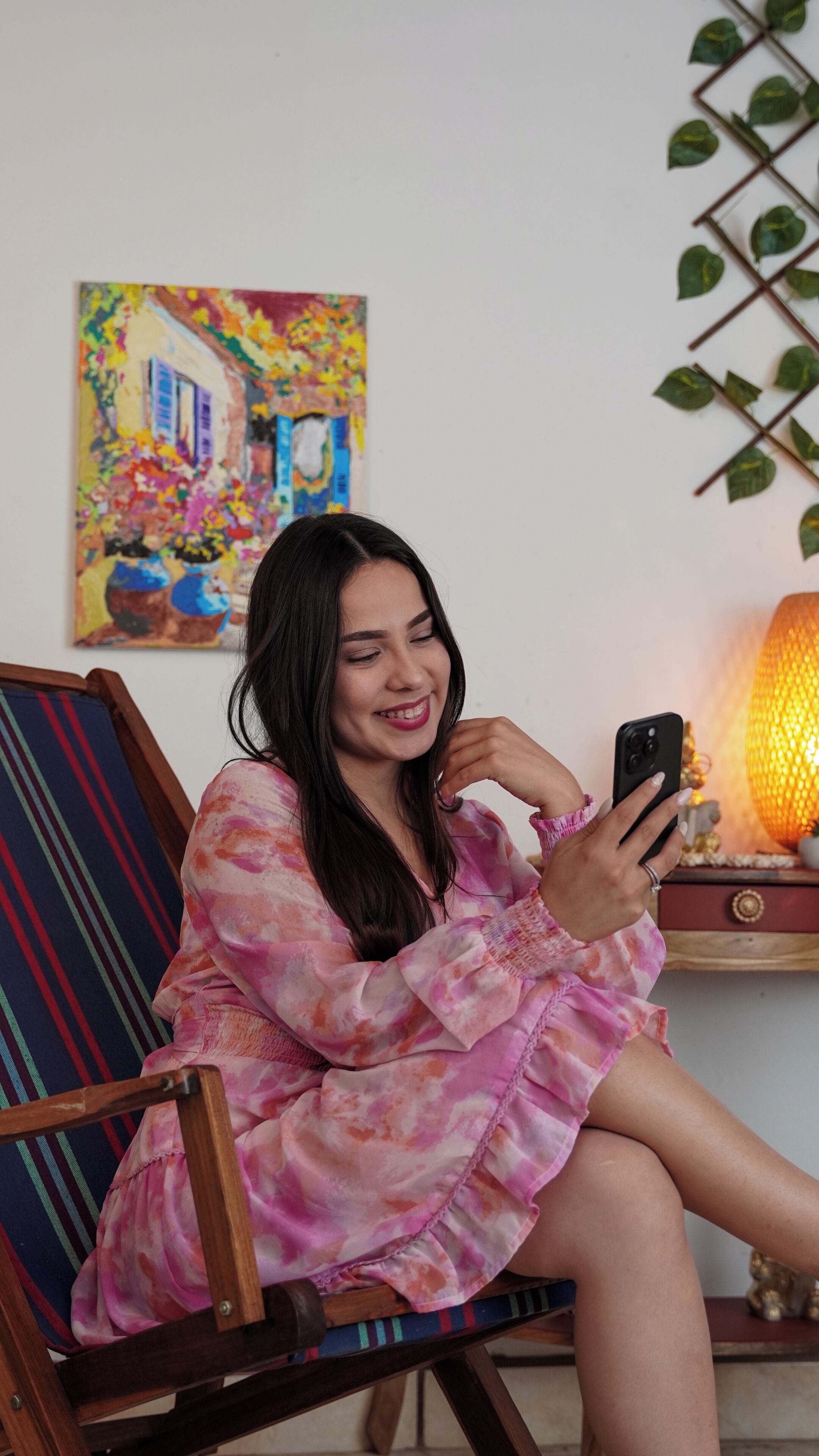 A person sitting on a chair with a colorful painting in the background.