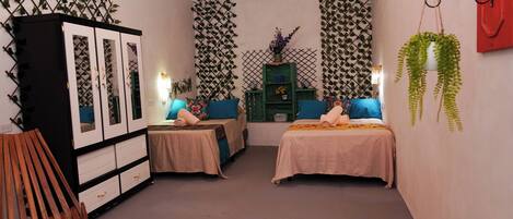 A room with two beds, a wardrobe, and decorative foliage on the walls.