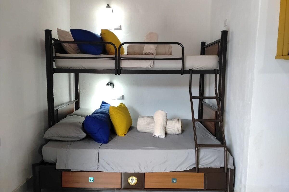 A bunk bed with two levels, each with pillows and a blanket. There are two drawers under the lower bunk.