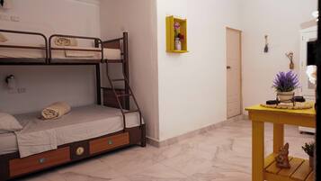 A bedroom with a bunk bed, a small table with a vase, and a door.