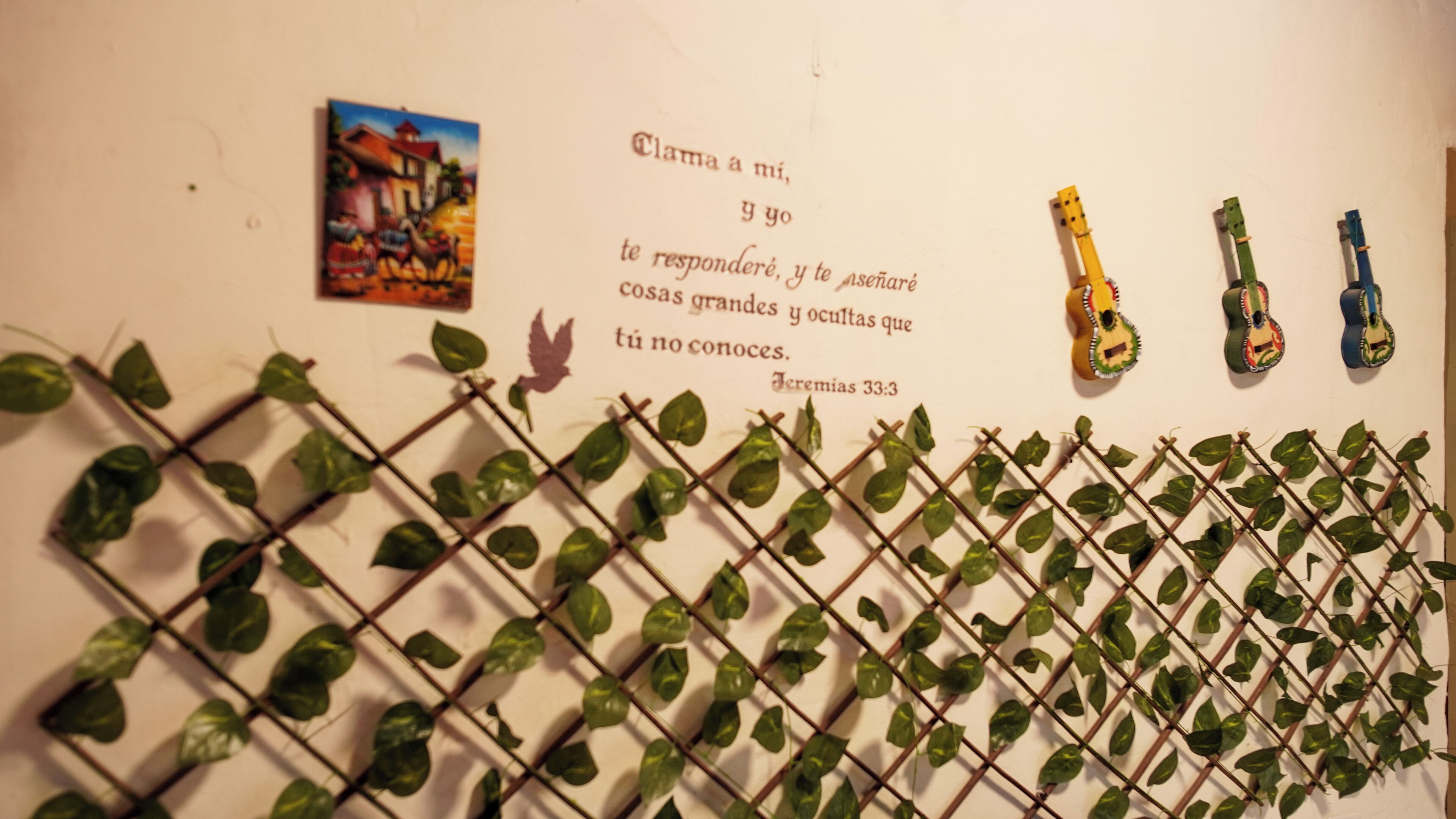 A wall with a quote, a painting, and three guitars.