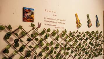 A wall with a quote, a painting, and three guitars.