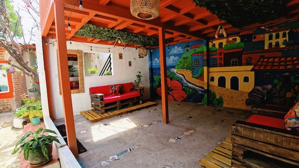 A room with a red sofa, a wooden bench, and a mural on the wall.
