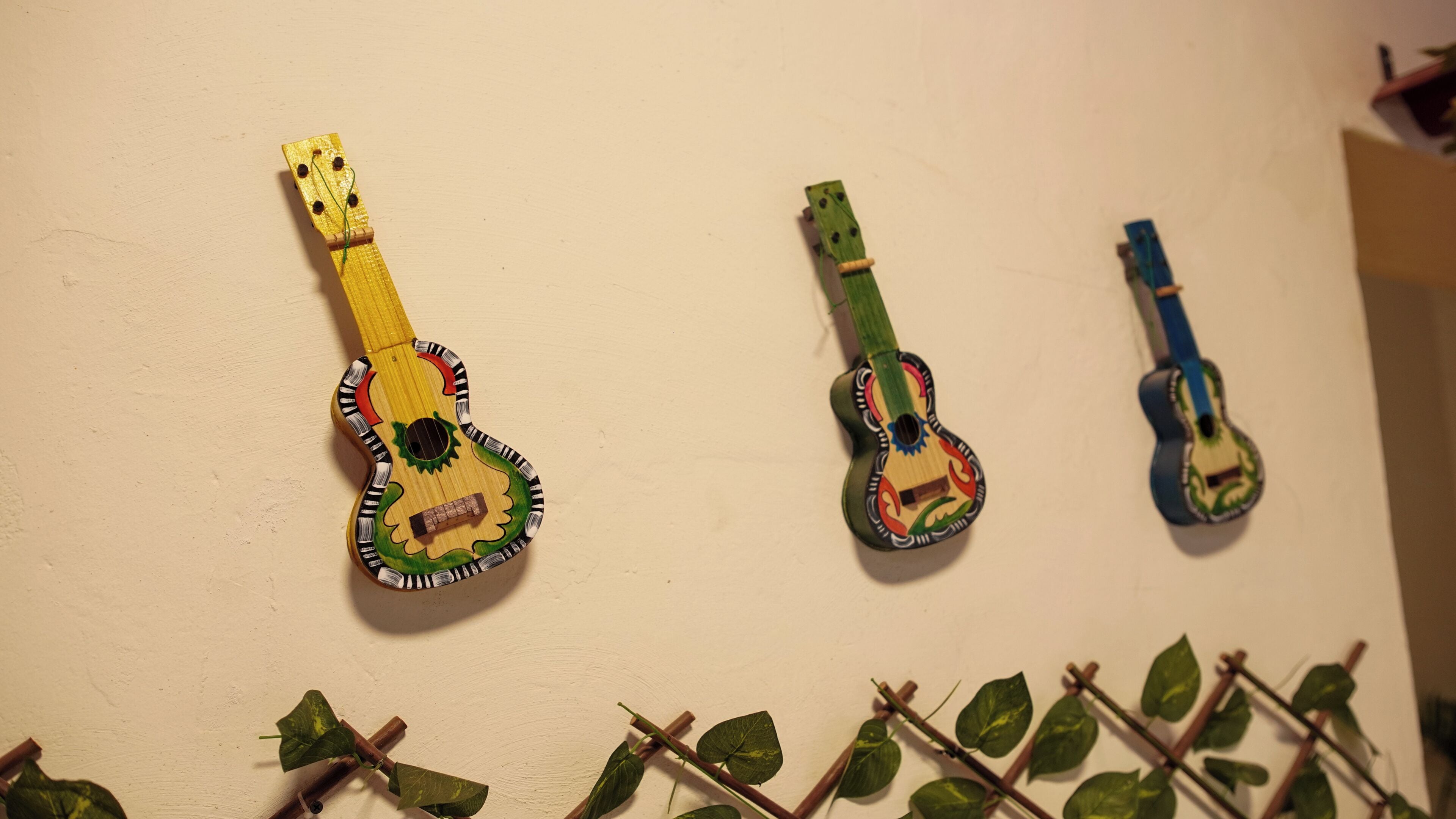 Three wall-mounted guitars of different sizes and designs.