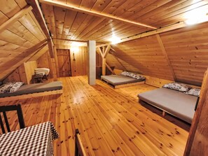 Ein Dachzimmer aus Holz mit zwei Betten, einem Tisch und einer Bank.